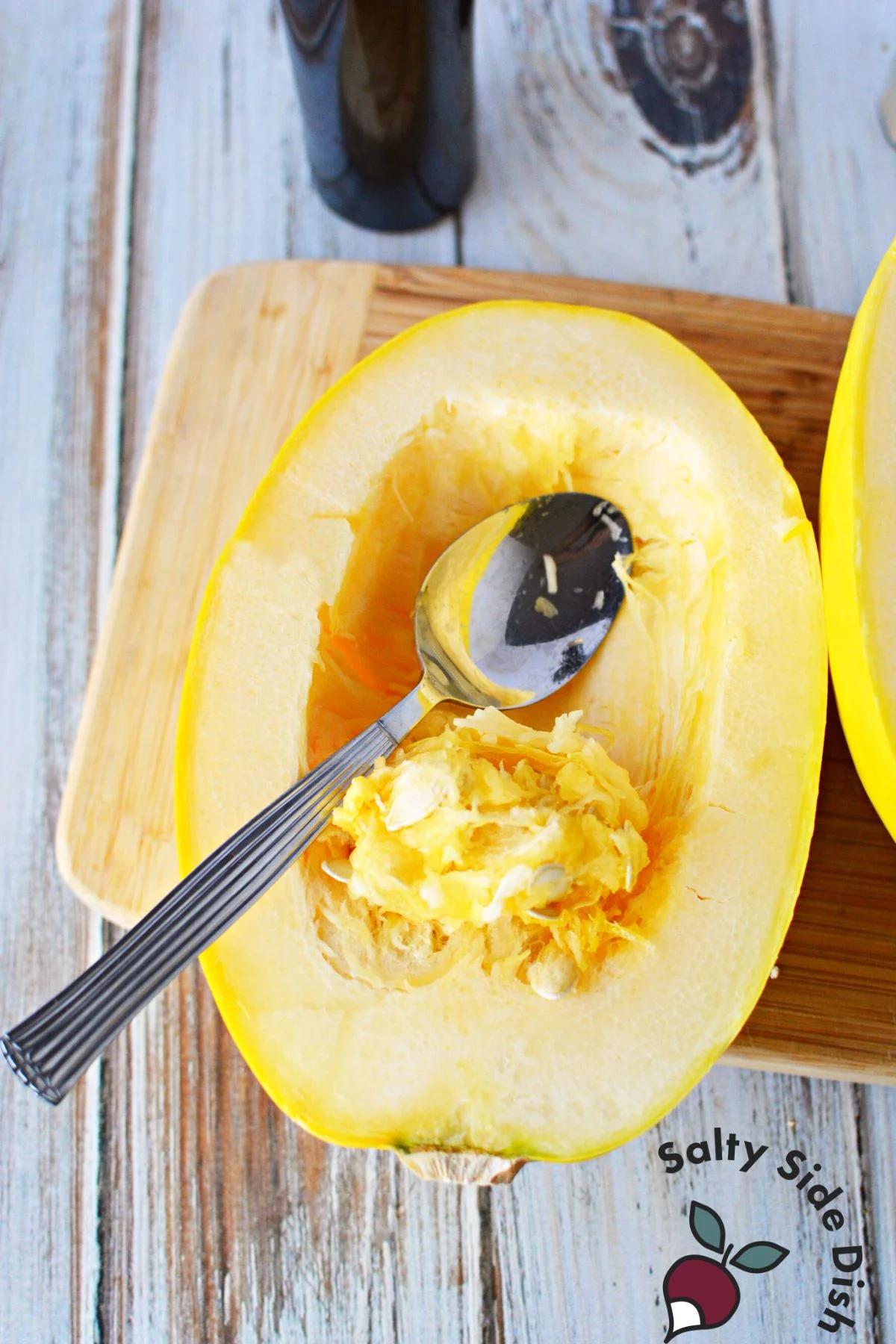 scrapping seeds out of spaghetti squash half.