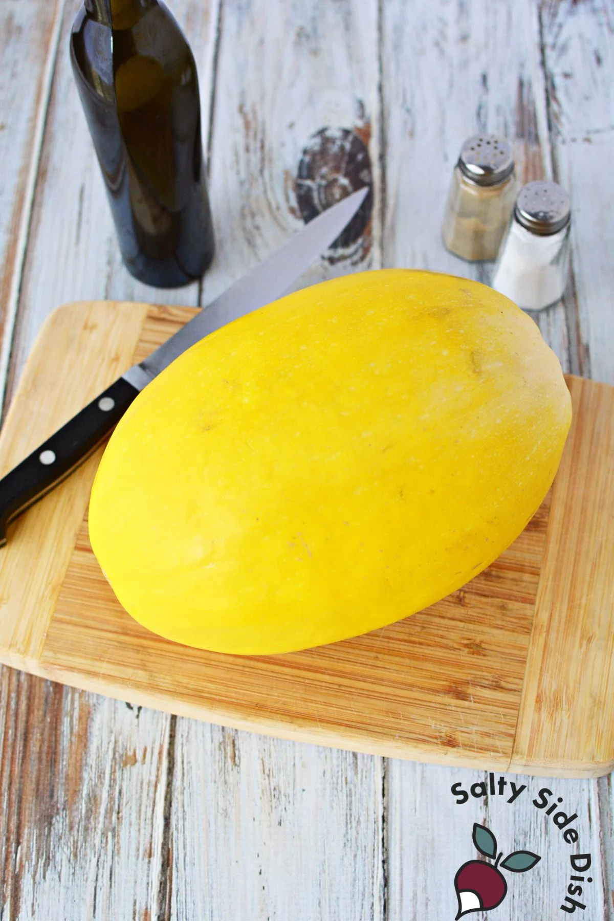 spaghetti squash on a cutting board with a knife.