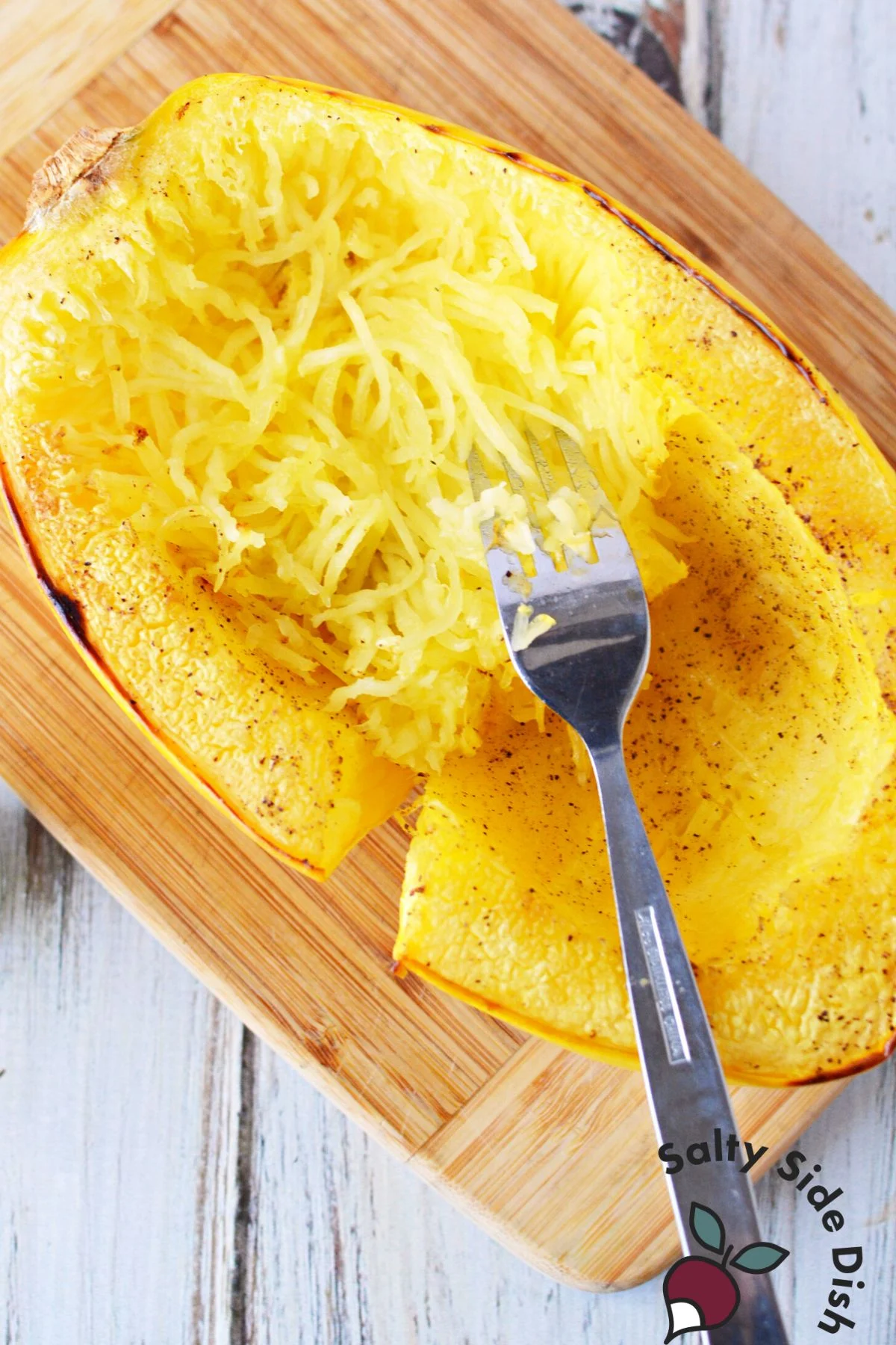 peeling squash strands from the inside of a cooked spaghetti squash.