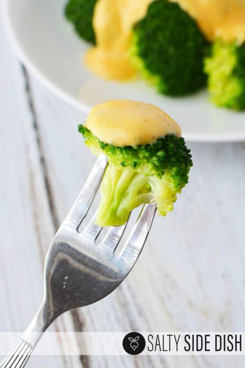 Cheese sauce on steamed broccoli on a fork and ready to eat