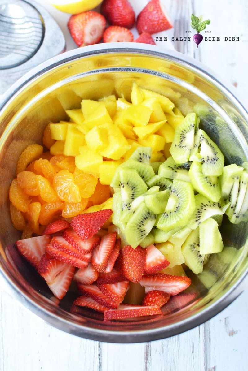 a bowl of variety of fruits like strawberries, oranges, kiwi, and pineapples to make a easy side dish bowl of fruit.