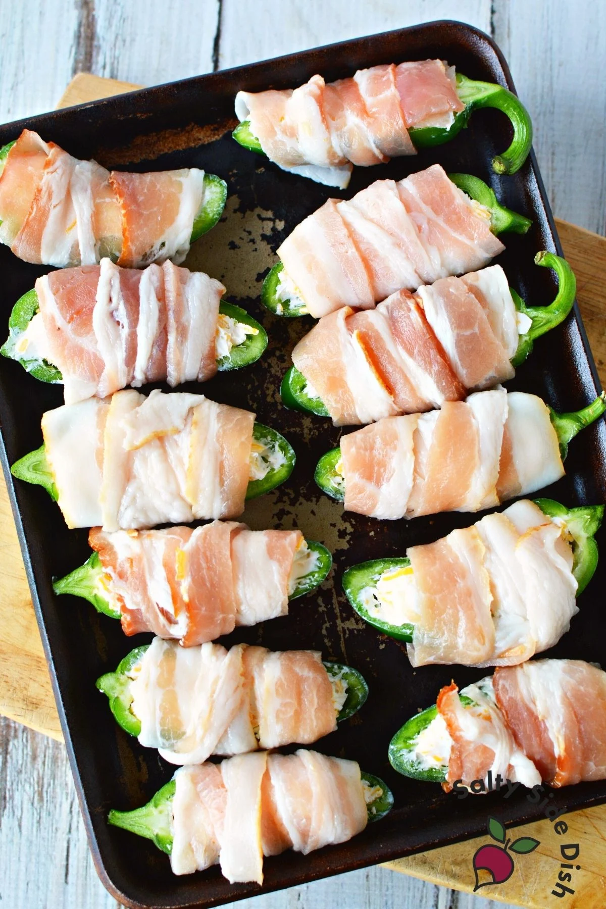 bacon wrapped jalapeno poppers on a rimmed baking sheet.