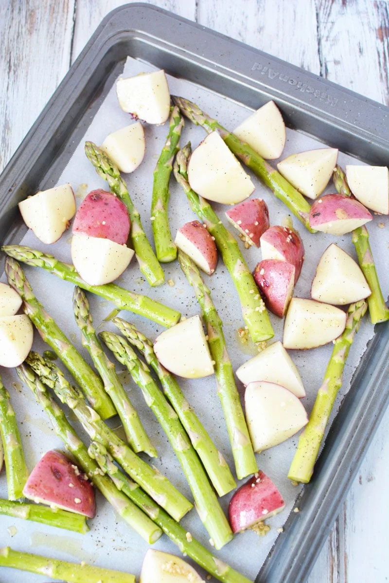 red potatoes and asparagus on a sheet pan with parchment paper