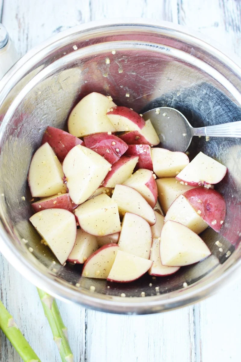 cut up red potatoes with garlic in a bowl