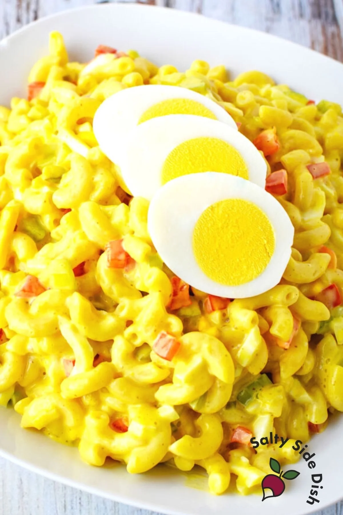 white plate with amish macaroni salad and boiled eggs on top.