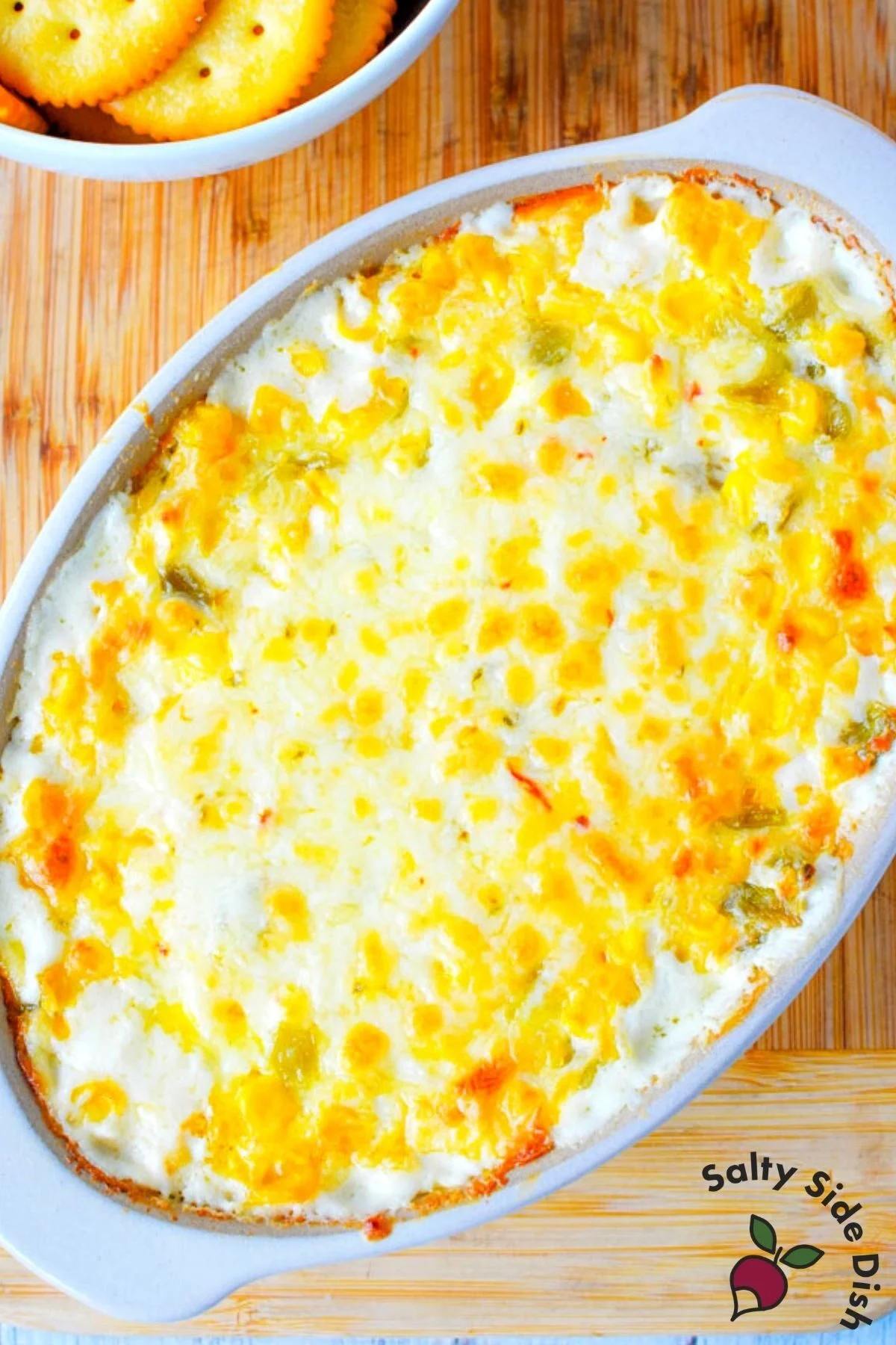 cracked out corn dip in a white baking dish with melted cheese.