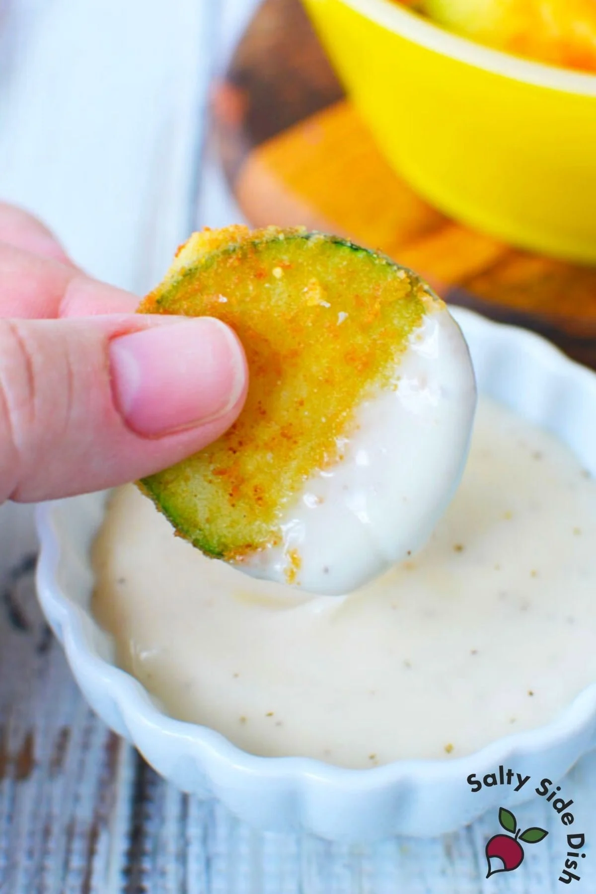 dipping fried zucchini into dip.