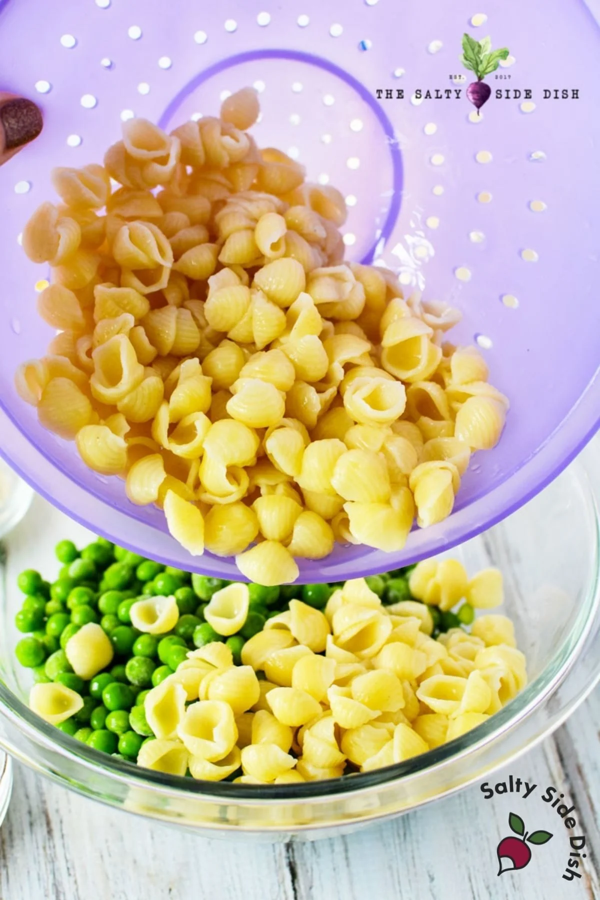 boiled pasta shells dumping into peas