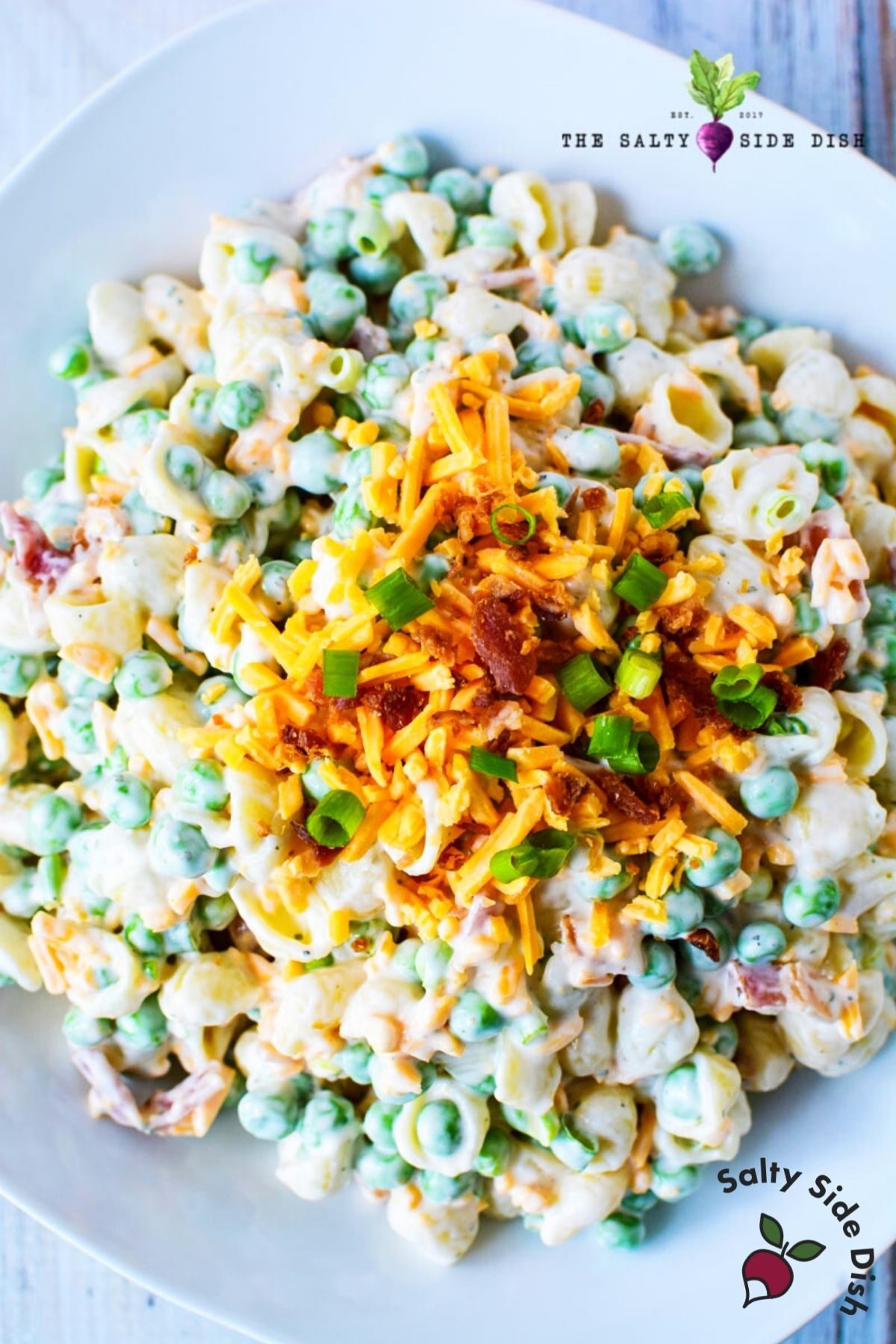 pea pasta salad on a plate with shredded cheese and bacon