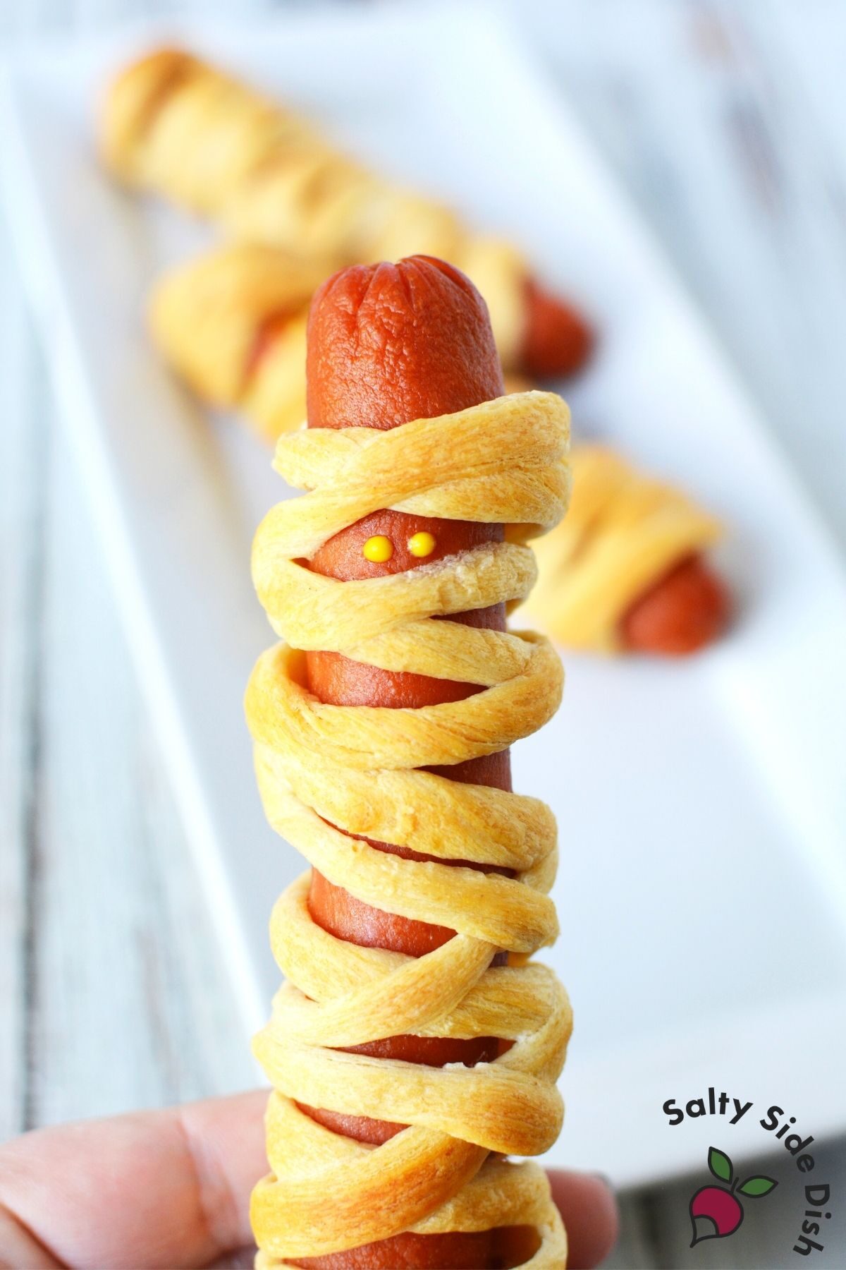 wrapping mummy dogs with crescent rolls and mustard eyes.