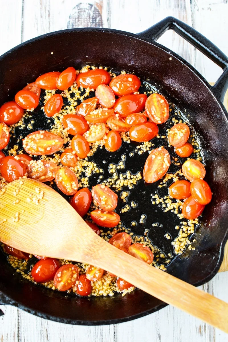 grape tomatoes and garlic in a cast iron pan.