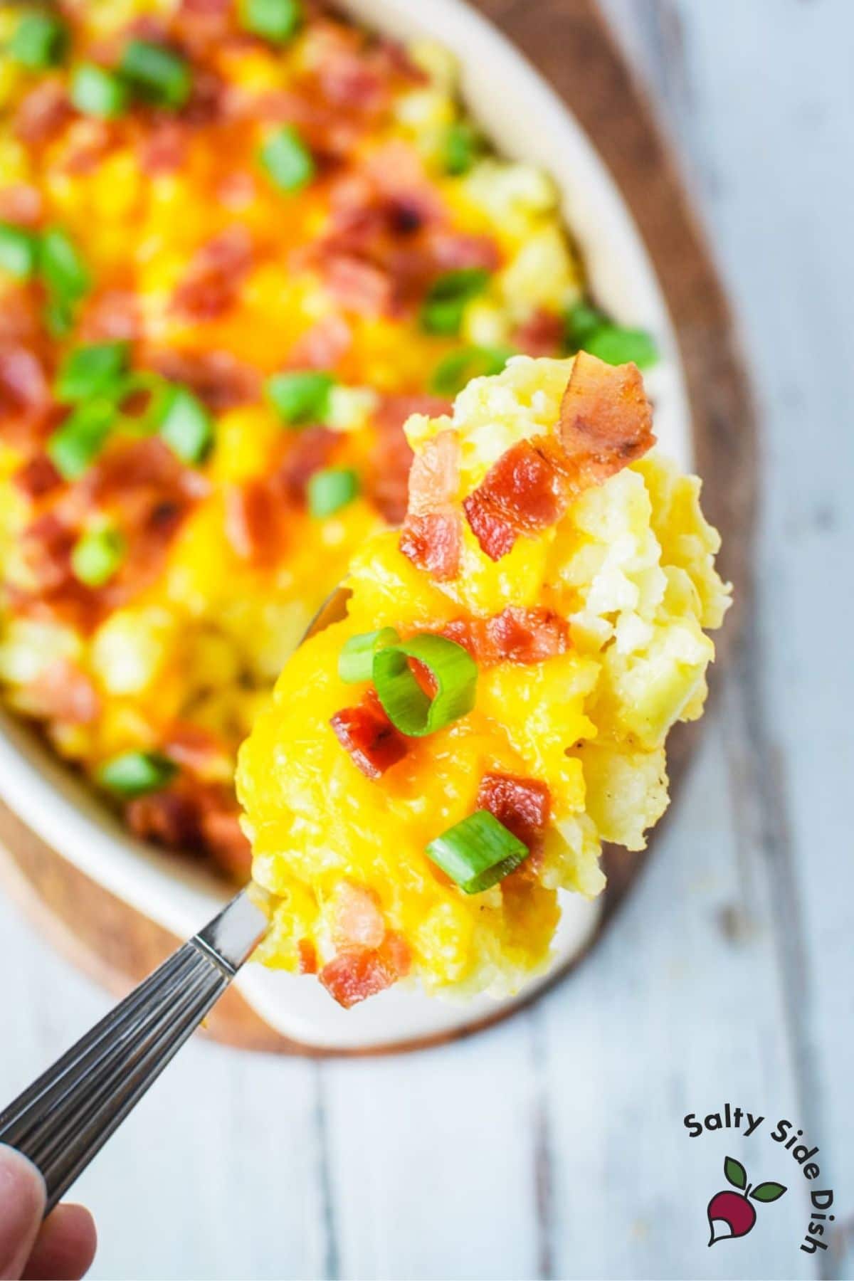 mashed cauliflower with cheese and green onions on a spoon