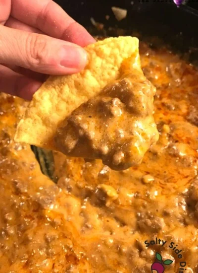 holding a beef enchilada chip with dip.