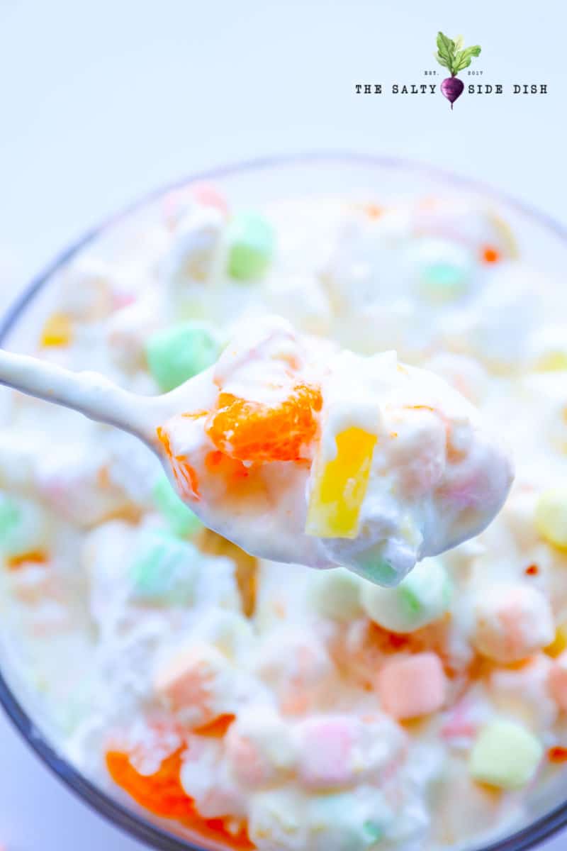 fruit salad fluff with cool whip on a spoon.