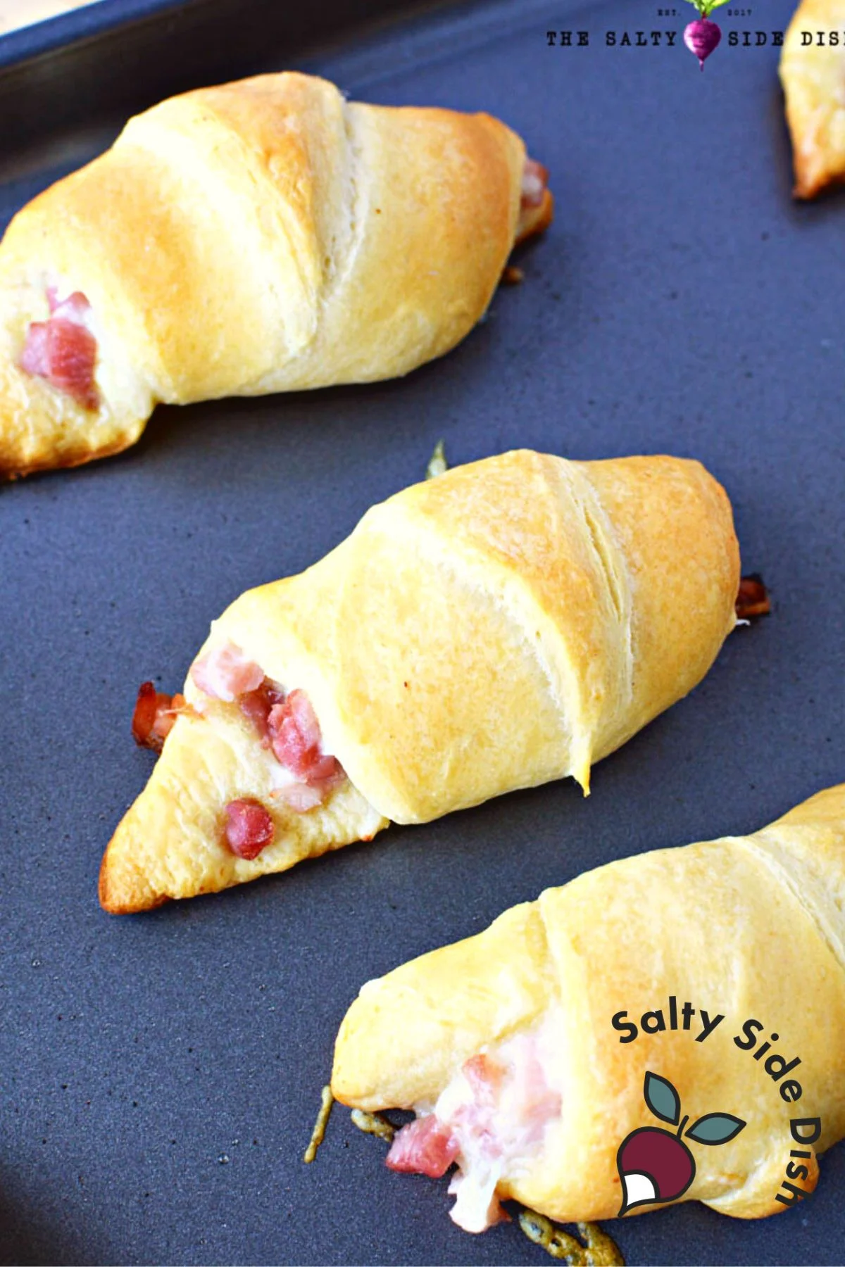 3 cooked pillsbury ham and cheese roll ups baked a golden brown on a baking sheet.
