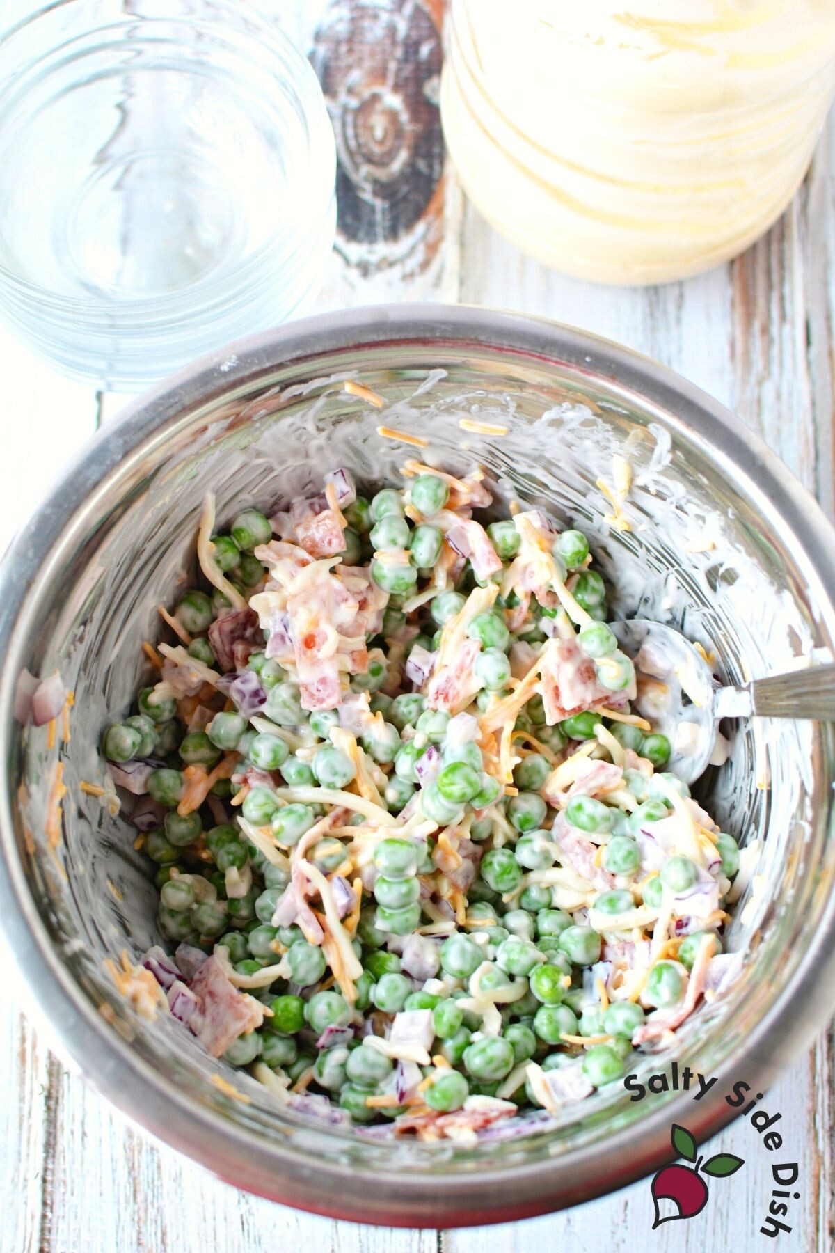 cheesy pea salad in a bowl being mixed.
