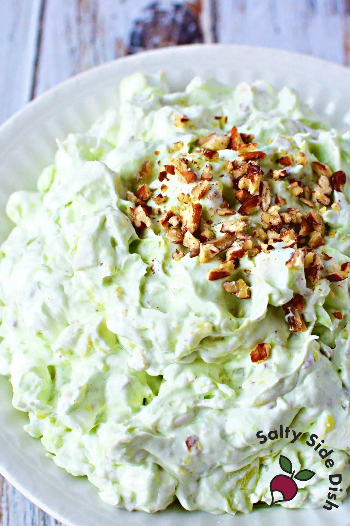 green goop pistachio salad fluff on a plate with nuts.