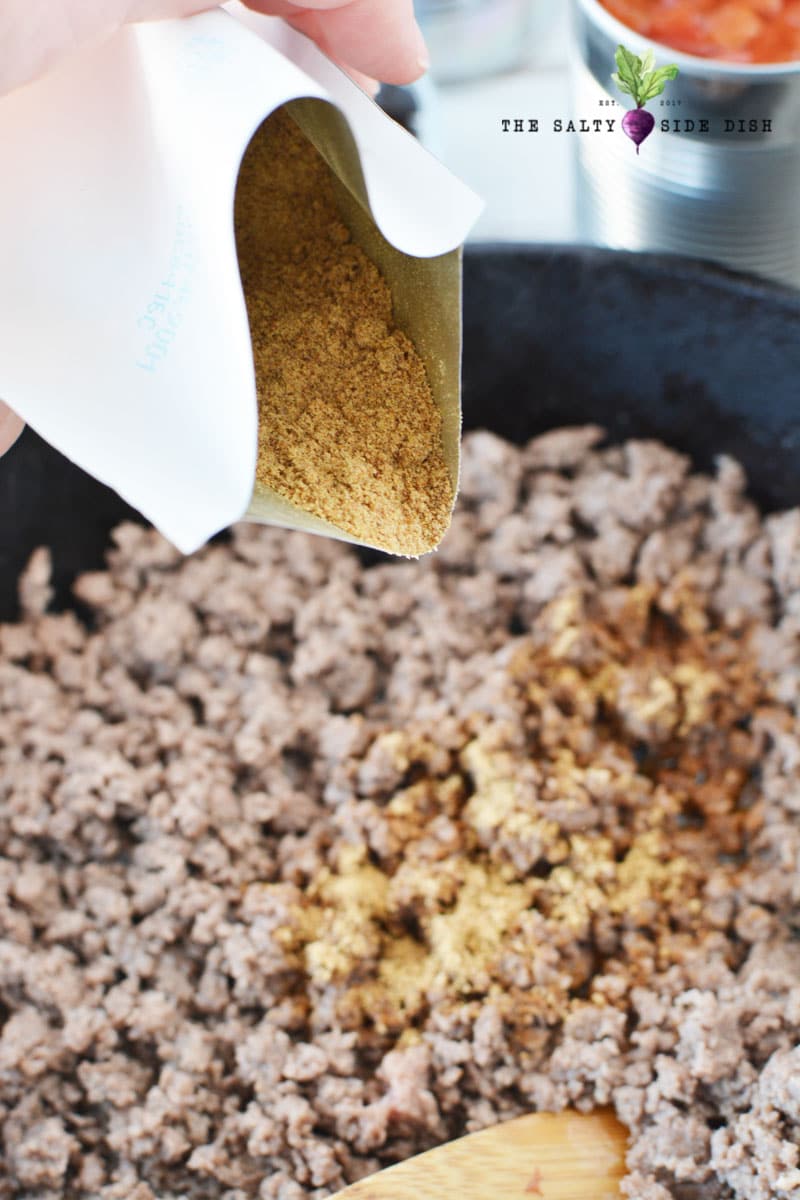 taco seasoning or homemade taco seasoning being dumped into the ground beef mixture