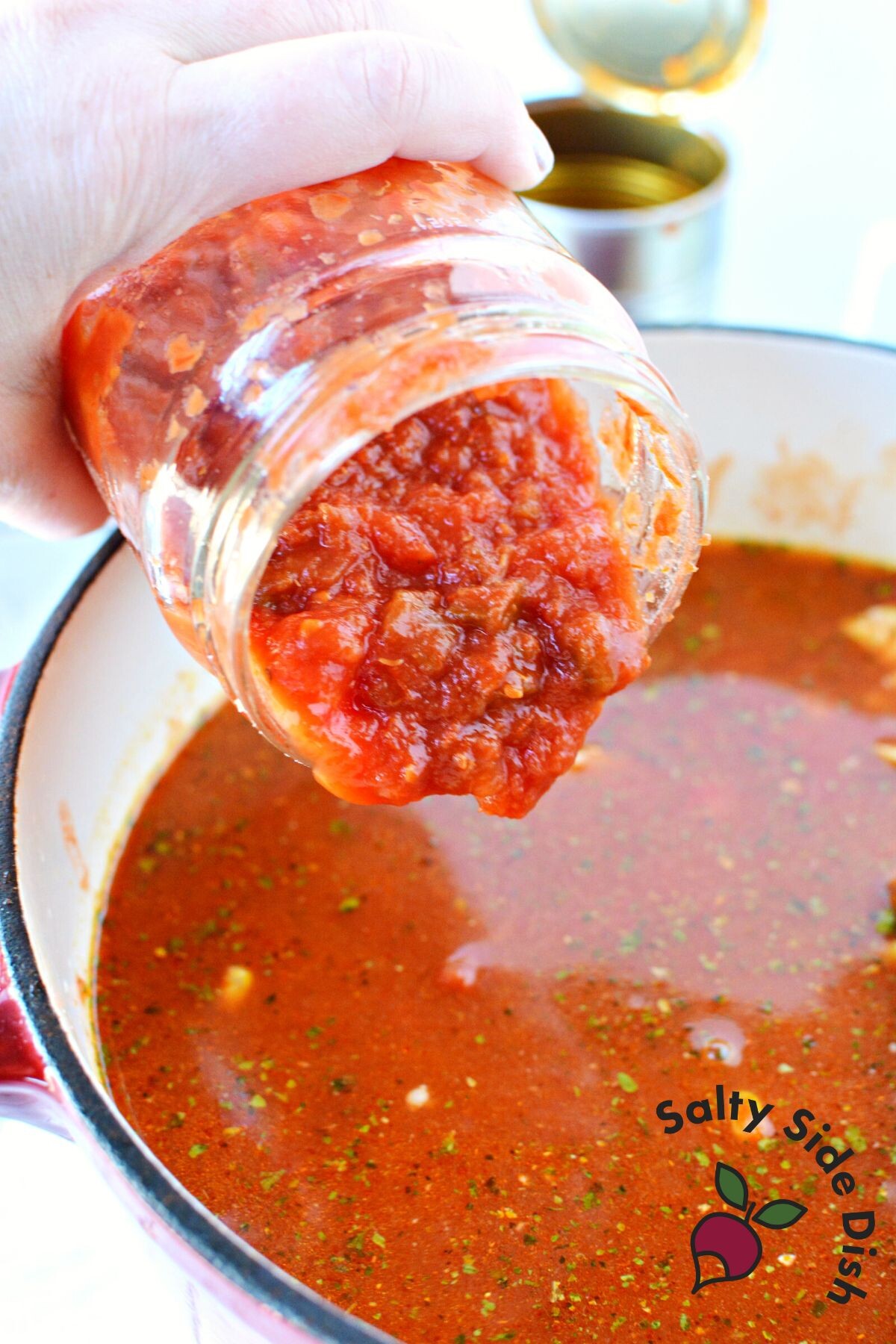 pouring jar of salsa into chili pot.