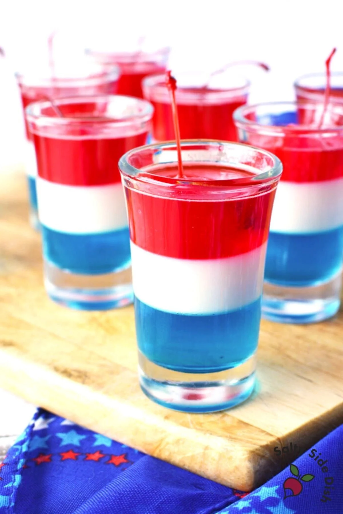 6 layered jello shots of red, white and blue sitting on a cutting board.