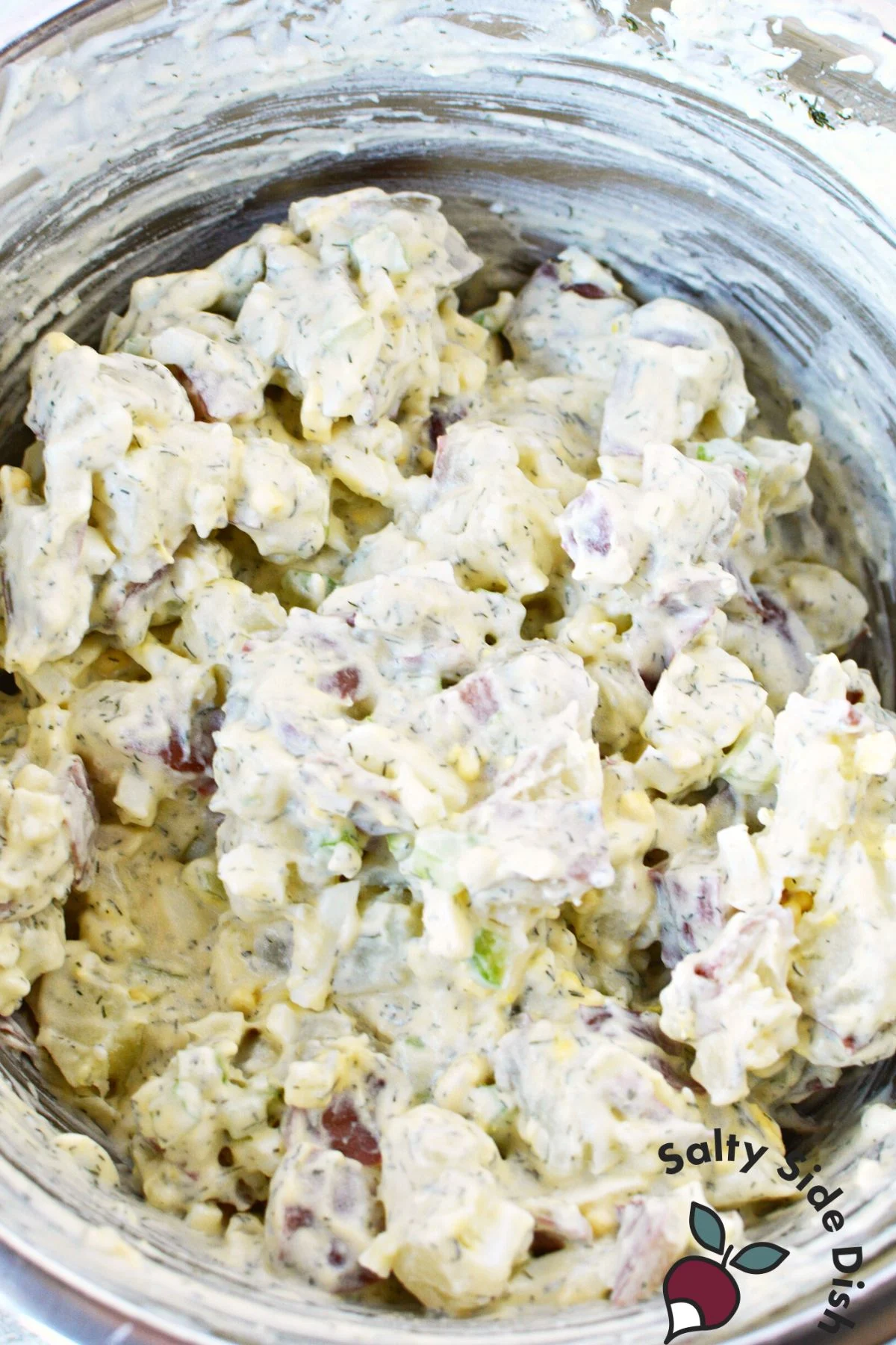 red potatoes and dill mixed with homemade dressing in a bowl.
