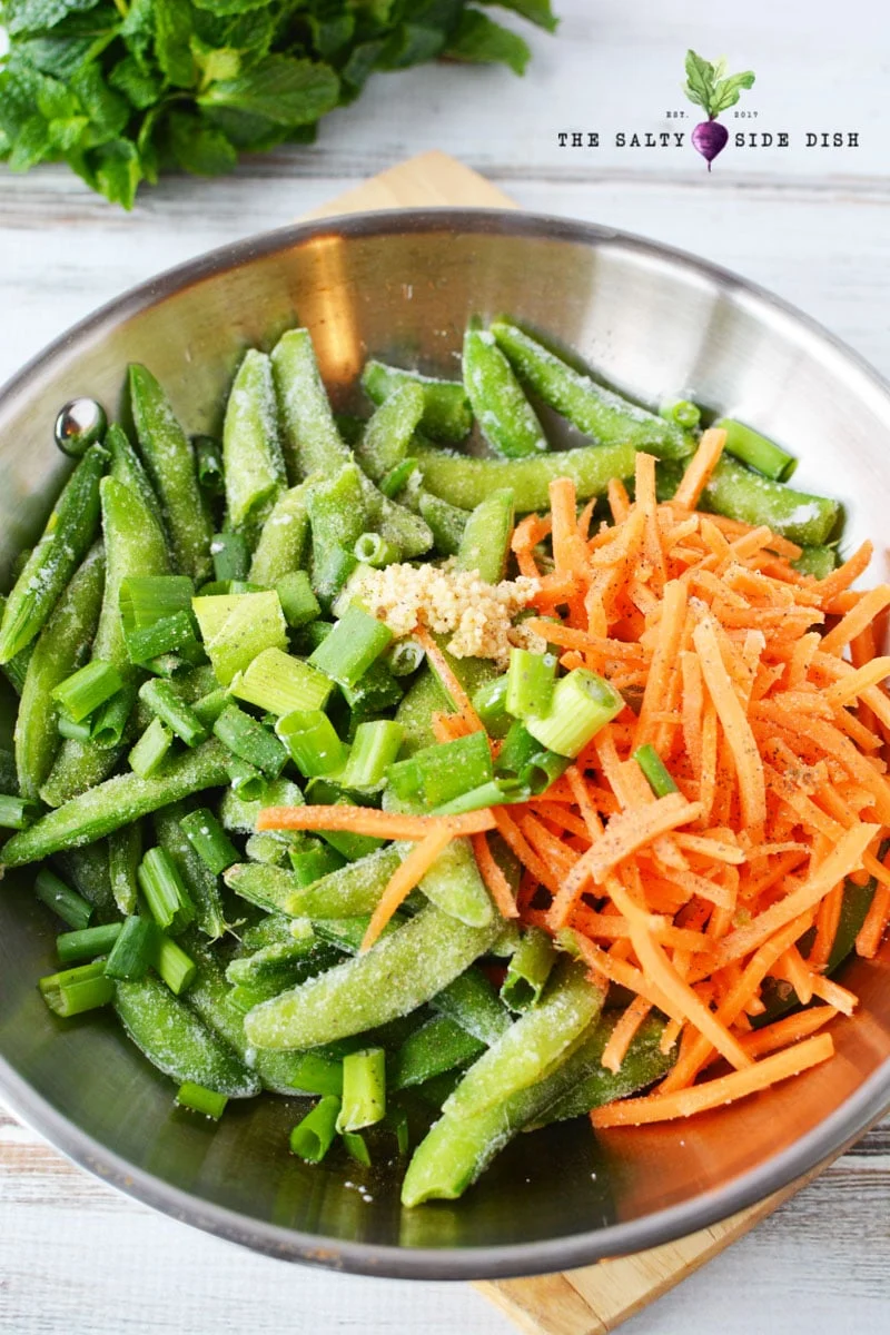 frozen sugar snap peas, minced garlic, matchstick carrots, and onions in skillet