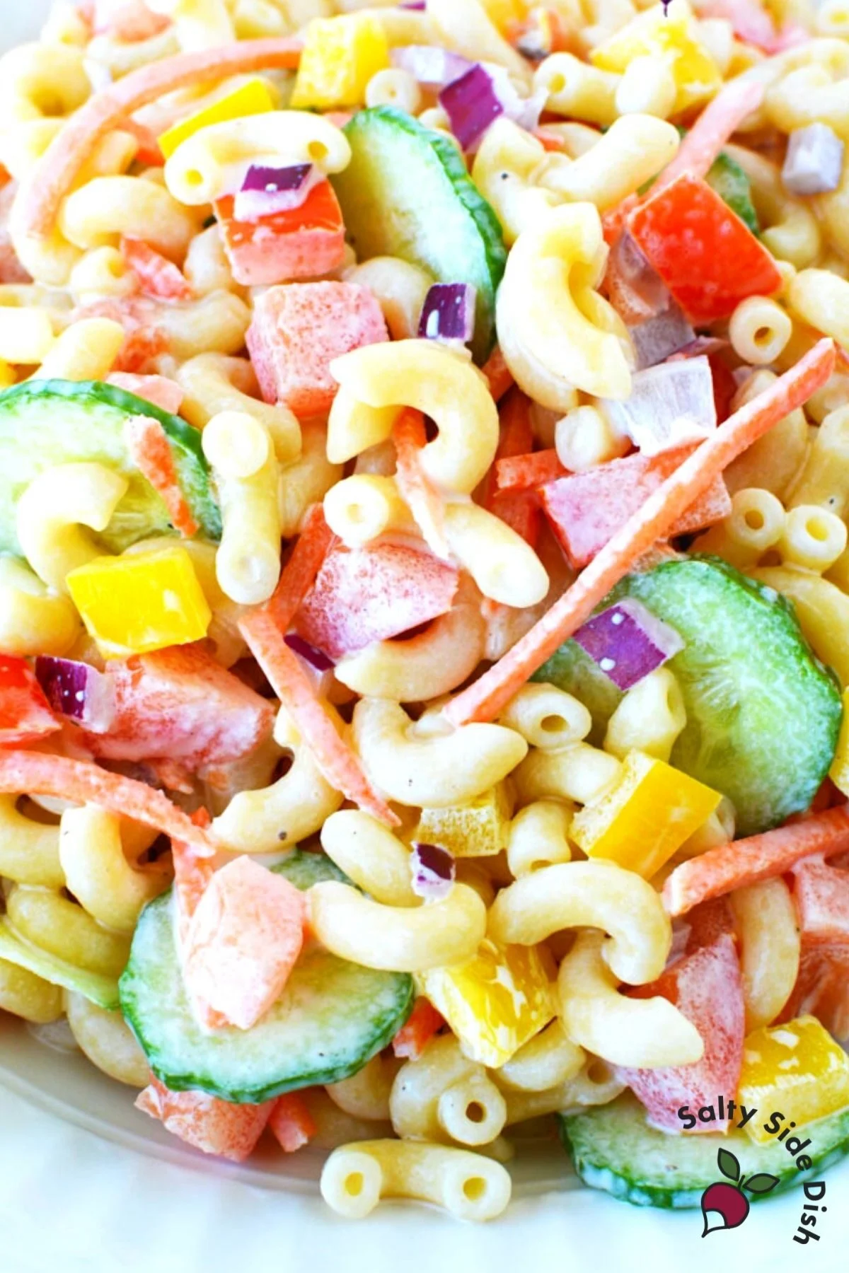 pile of cooked macaroni and fresh vegetables in a salad.