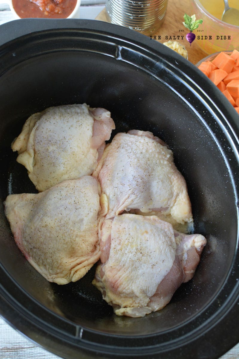 chicken thighs in slow cooker seasoned with salt and pepper