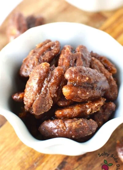 white bowl of candied pecans sitting on a wooden table