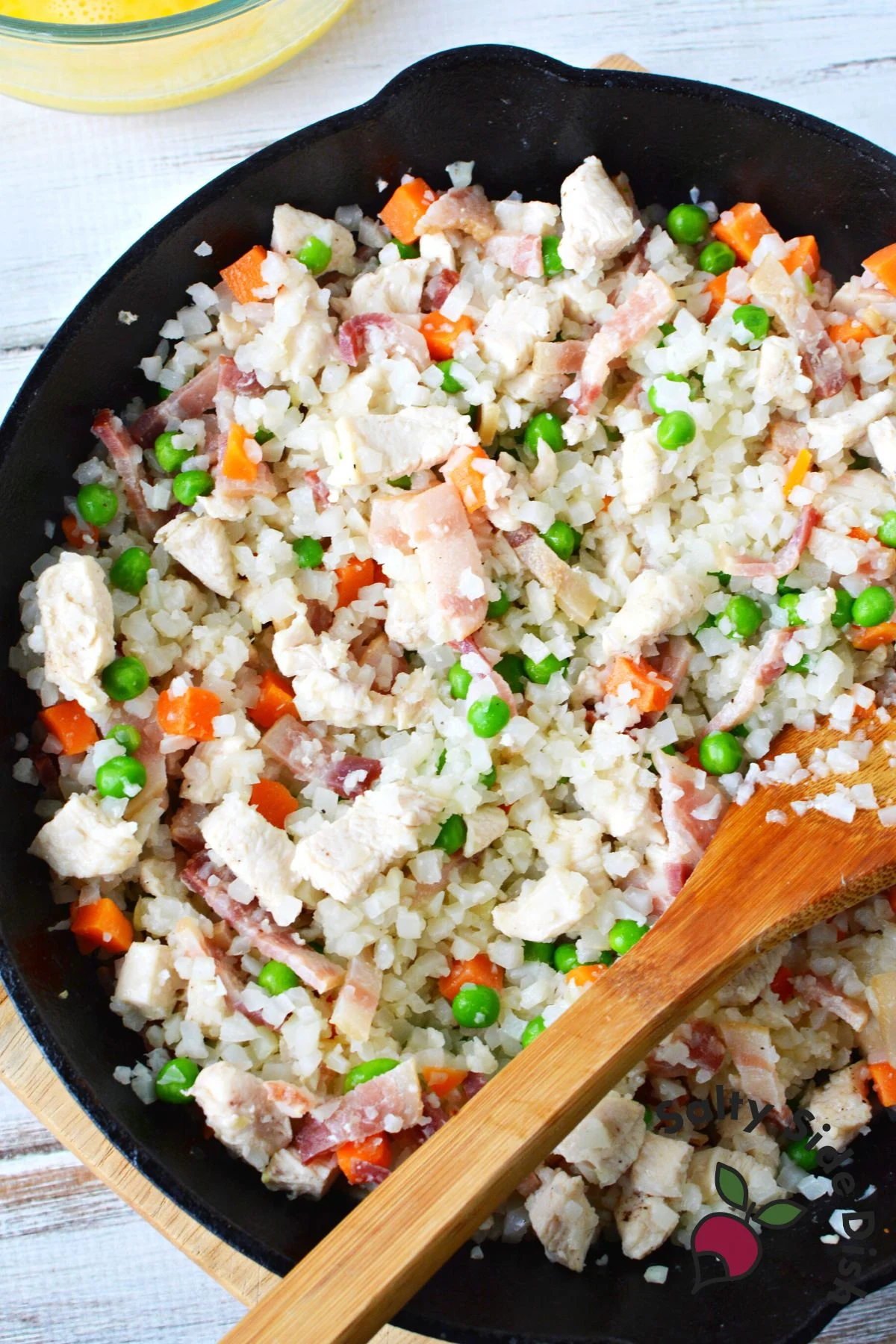 cauliflower riced in pan with frozen vegetables before eggs.