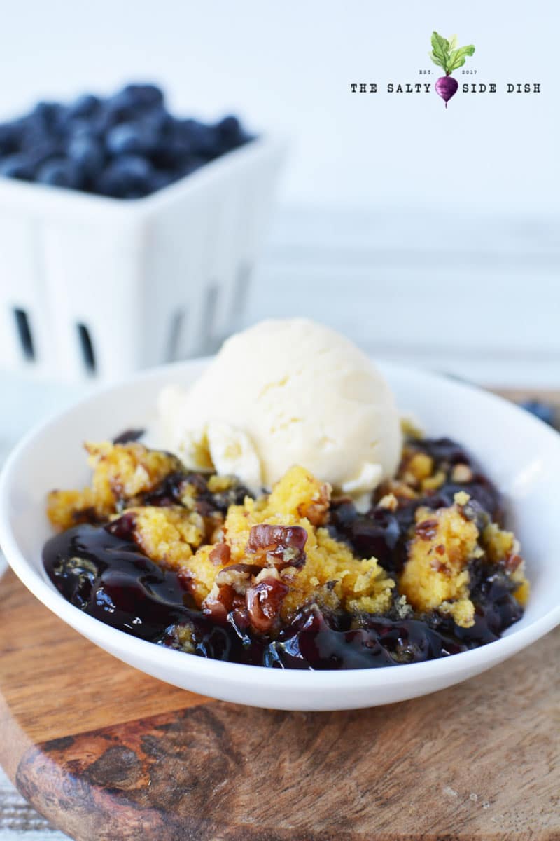 blueberry dump cake is a blueberry cobbler made with yellow cake in a crockpot served with fresh blueberries and a vanilla ice cream