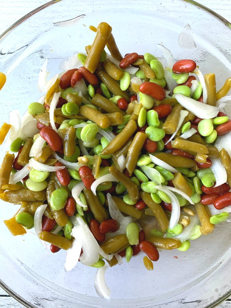3 bean salad with onions mixed in a bowl with vinegar and sugar