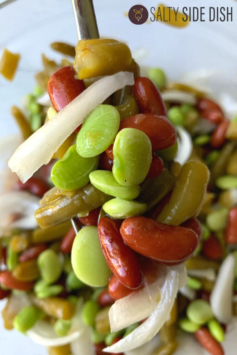 Lima bean salad with onions and kidney beans balanced on a serving spoon