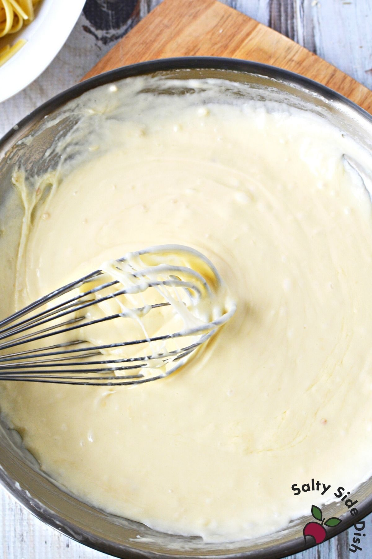 stirring low carb alfredo sauce with a whisk.