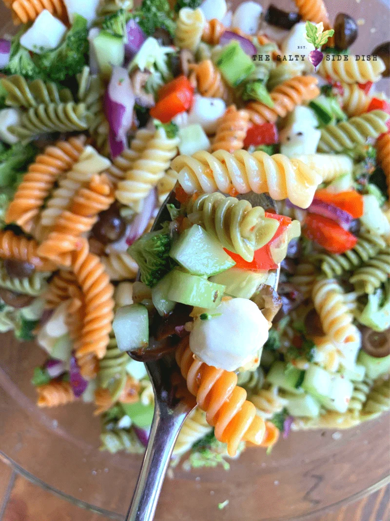 Tri Color Curly pasta on a fork with red peppers, black olives and mini cheese ready to eat