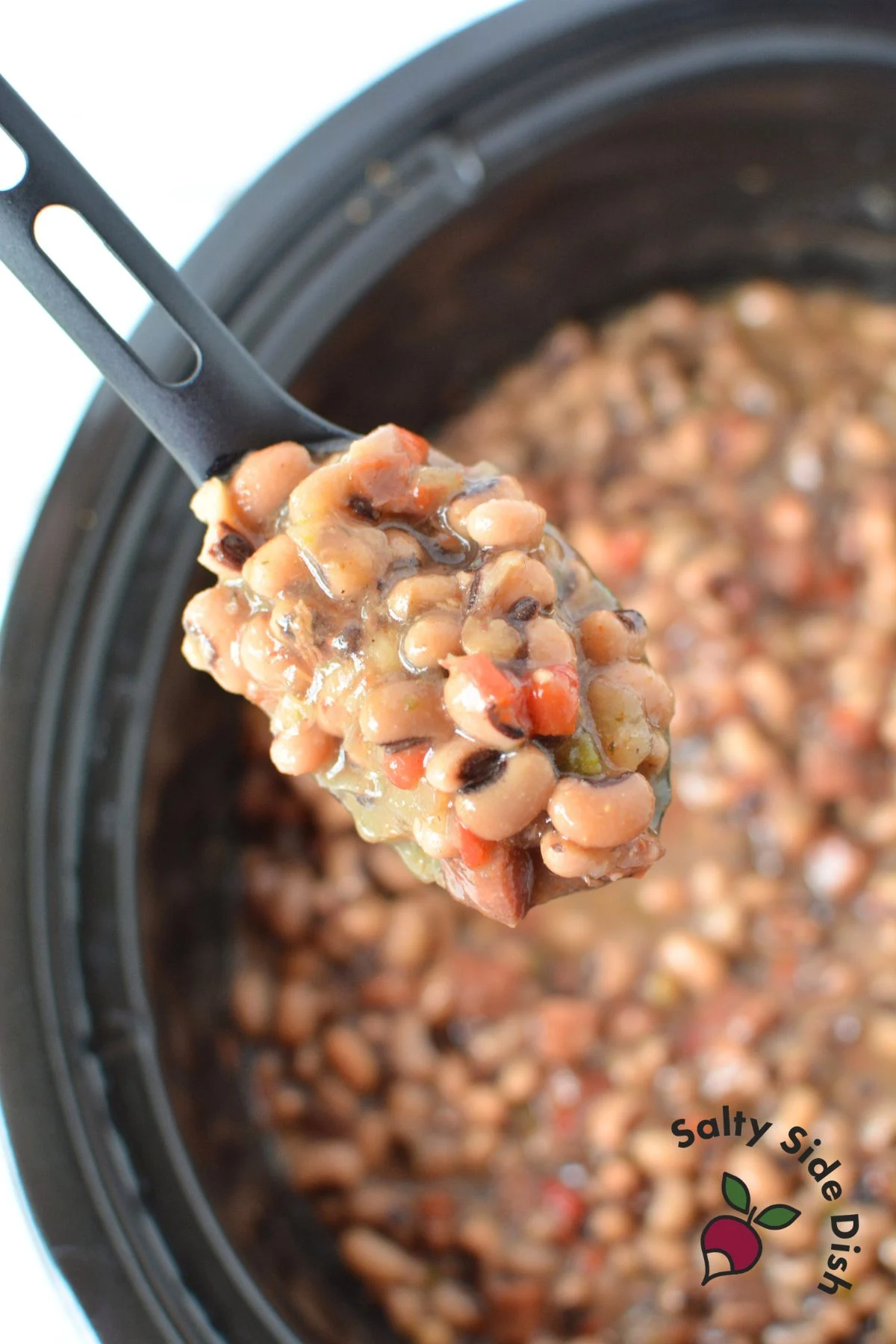 spoonful of black eyed peas in a crock pot.