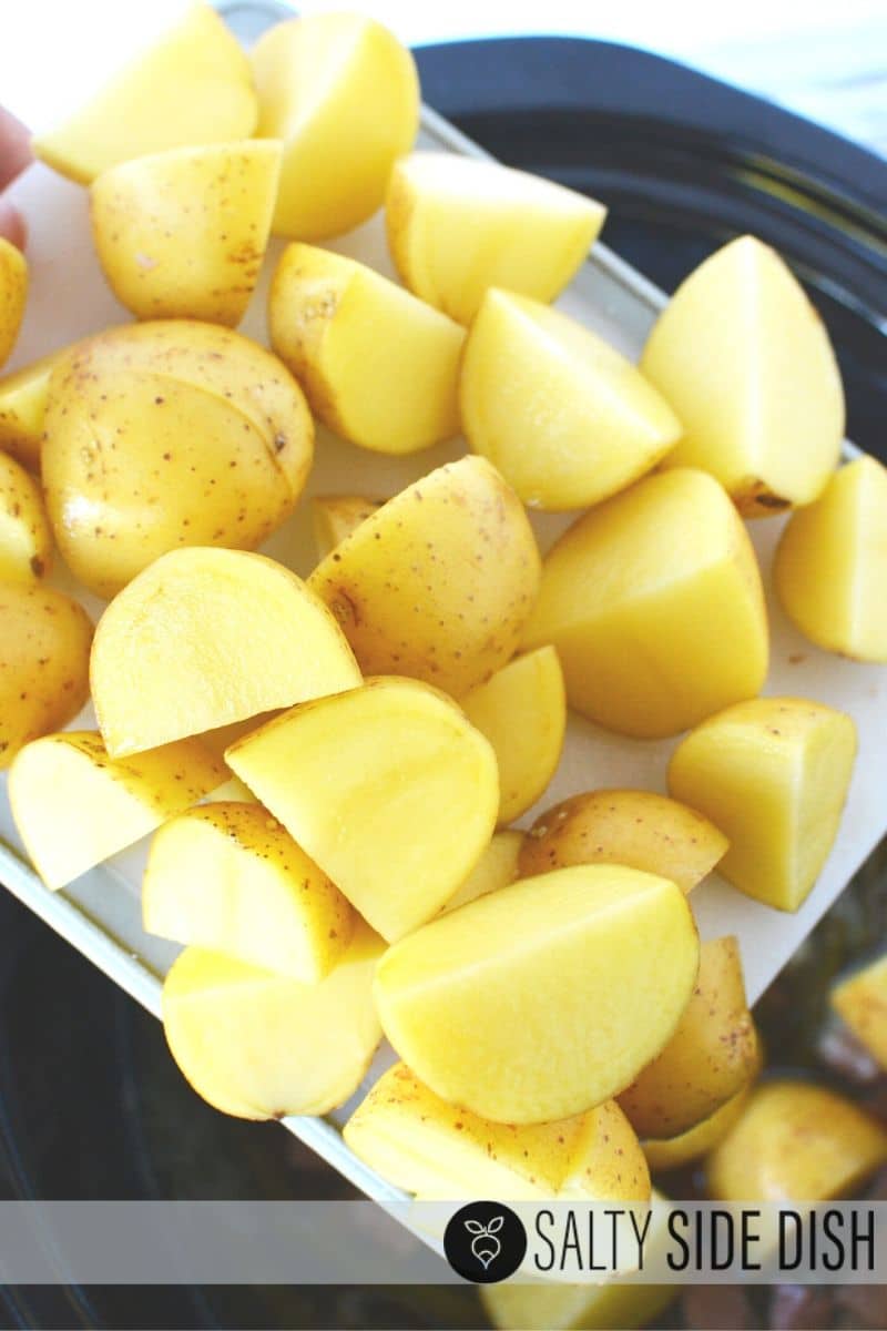 yellow yukon potatoes quartered and being dumped into crock pot