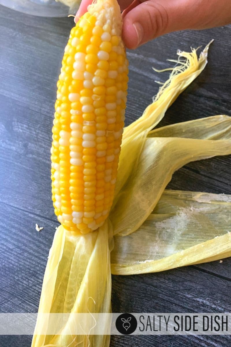 Removing the husk from an ear of corn.
