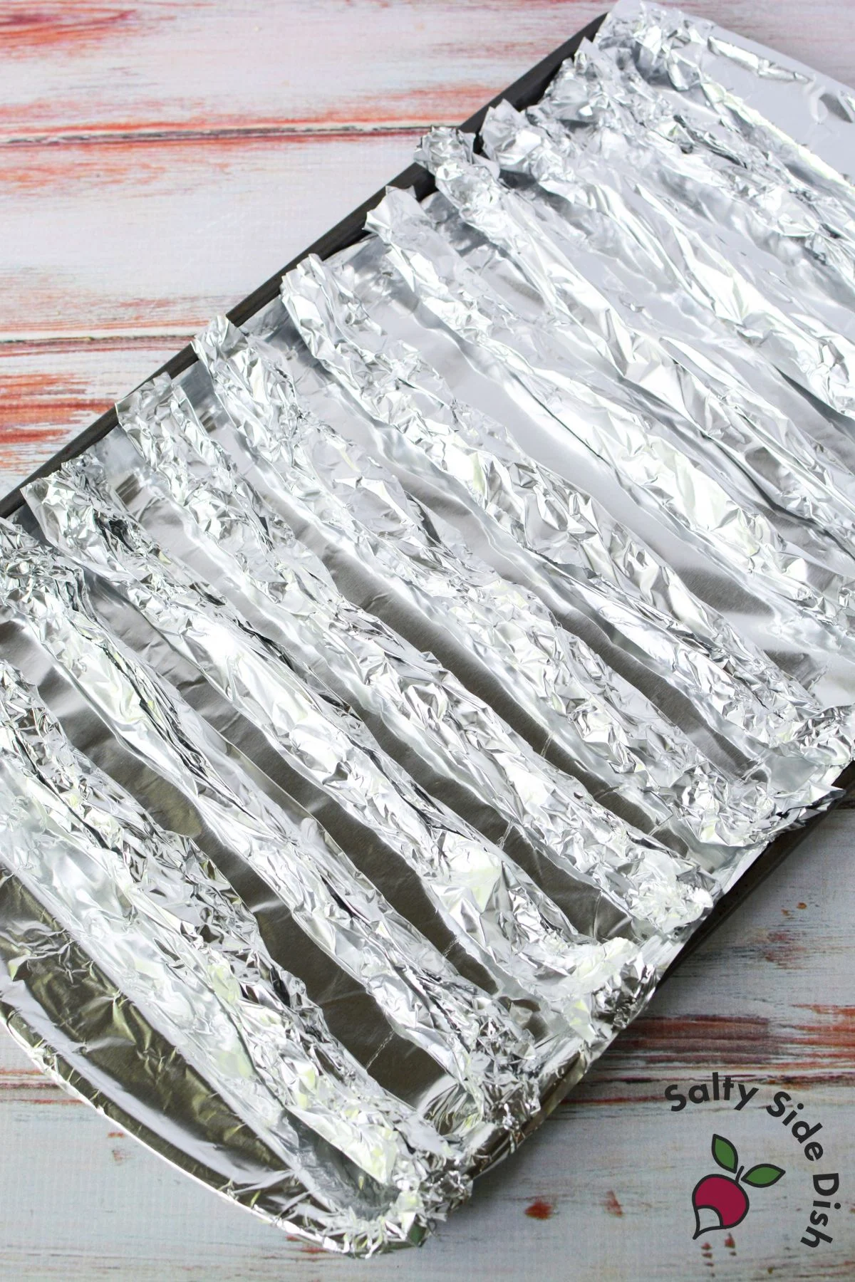 Rolled foil strip used as a DIY rack for cooking bacon in the oven