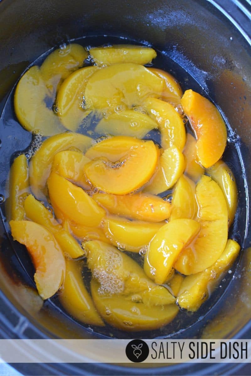 canned peaches with syrup at the bottom of a crock pot