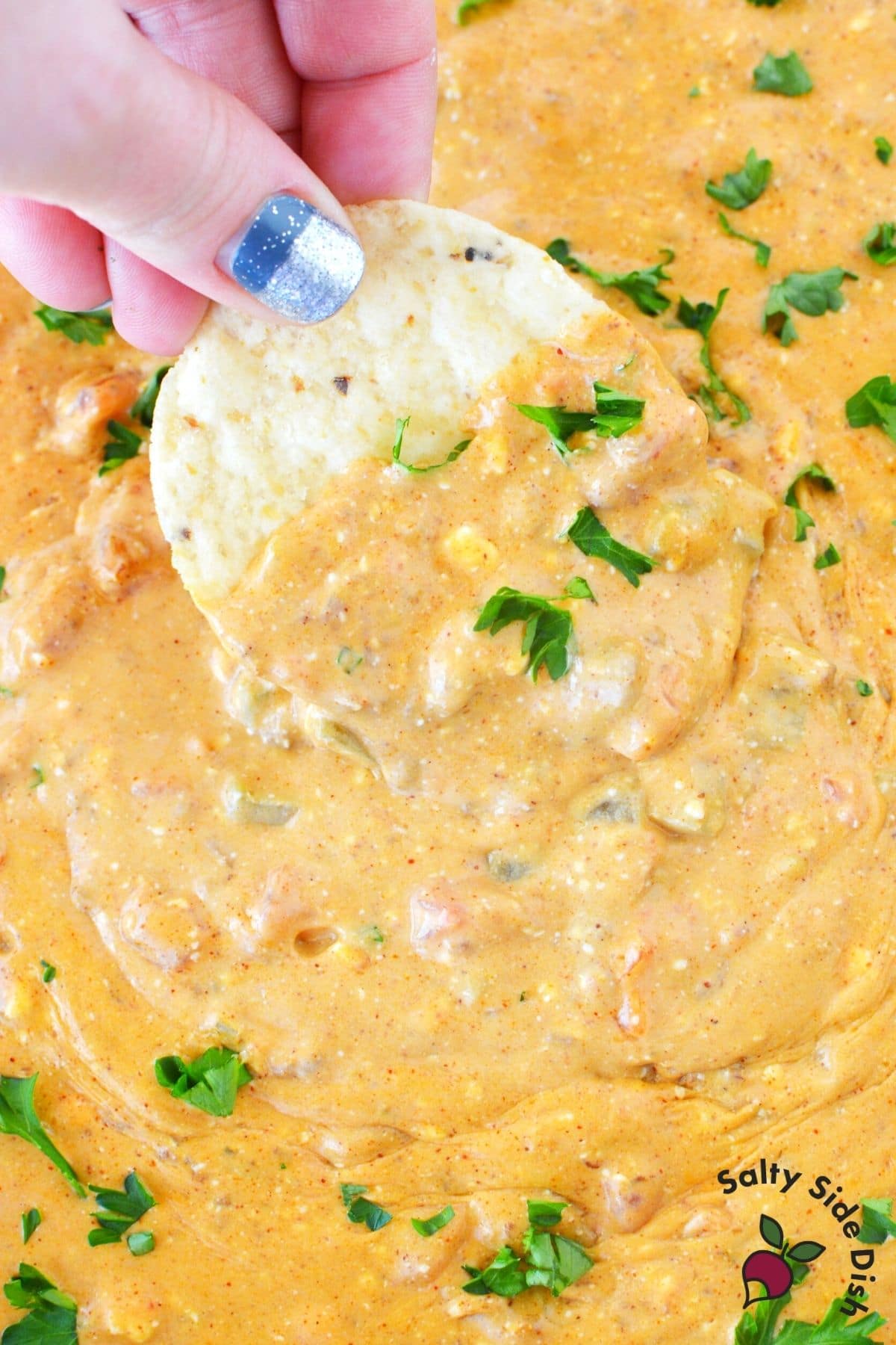chili cheese dip with cream cheese and a chip dipping into it