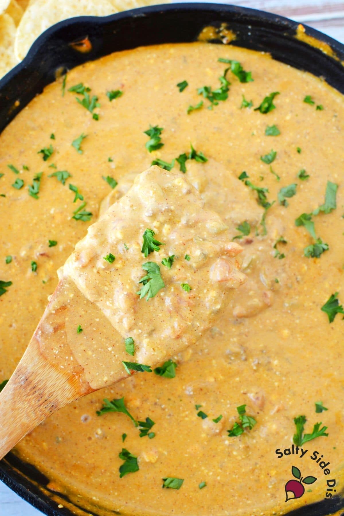 chili cheese dip being stirred by a wooden spoon