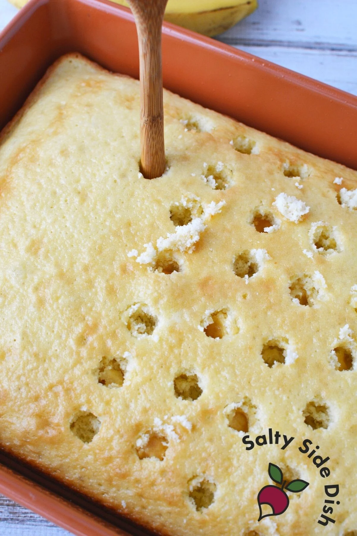 poking poke cake with a wooden spoon.