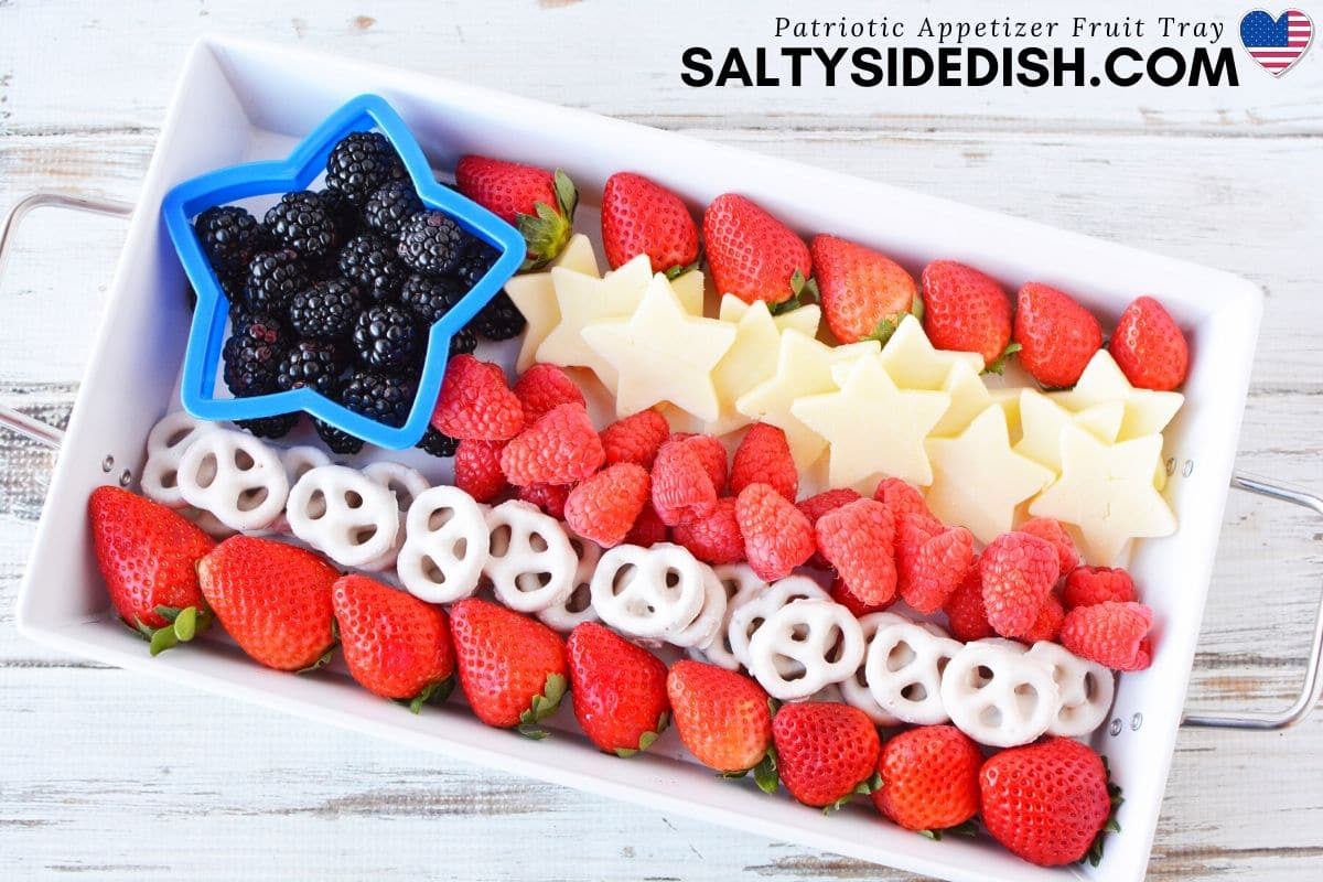 American flag fruit tray with cheese stars, blackberries in a cookie cutter and white chocolate covered pretzels