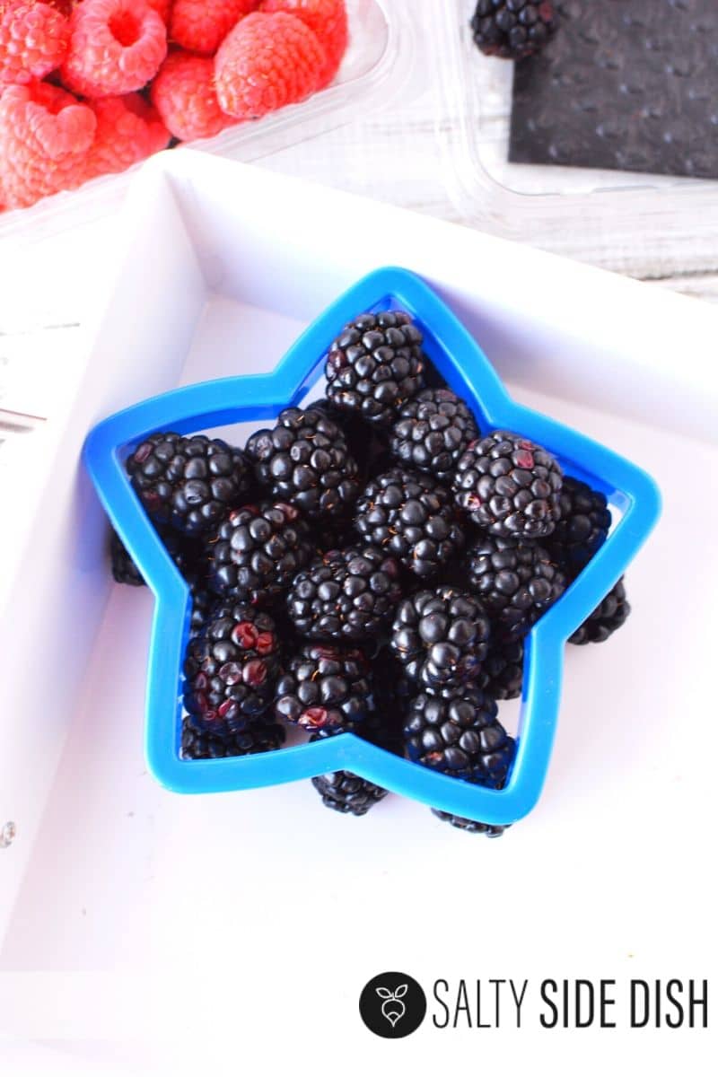 Blackberries make a perfect blue fruit sitting in a cookie cutter on a white tray