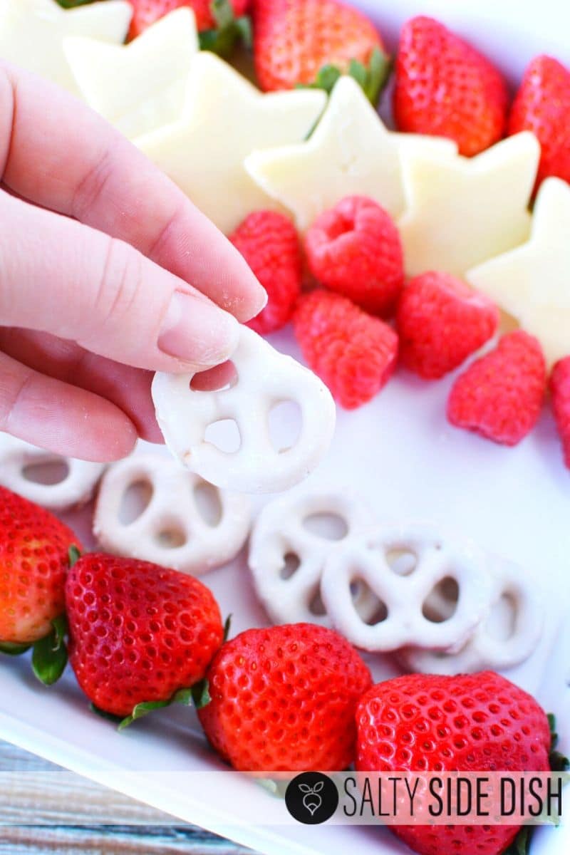 add sweet pretzels to your tray for a sweet treat with hand holding white chocolate covered pretzel on tray