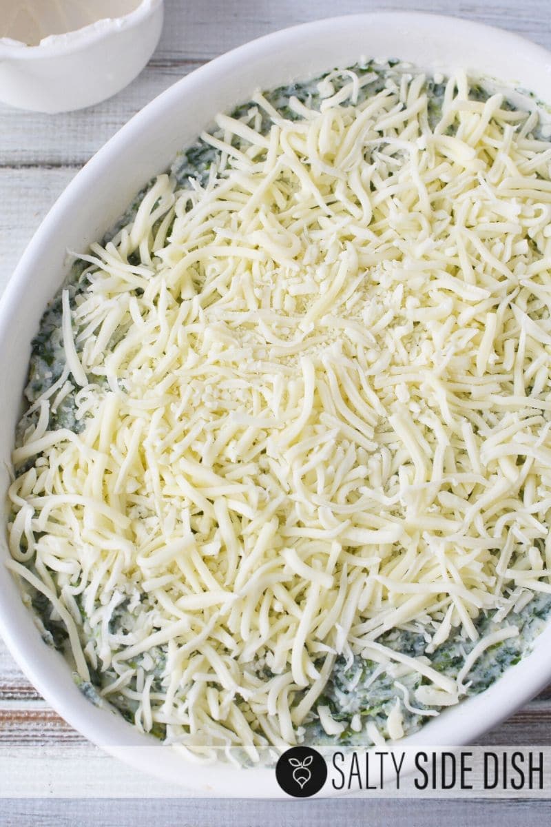 Smother top of spinach mashed potatoes with tons of cheese as noted in this picture of a white casserole dish with shredded mozzarella