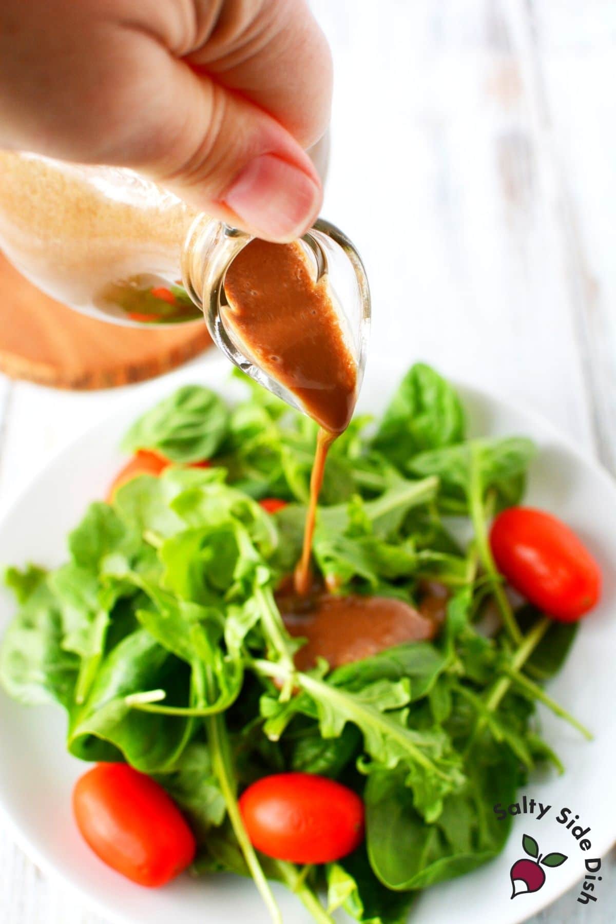 balsamic dressing being poured over a salad