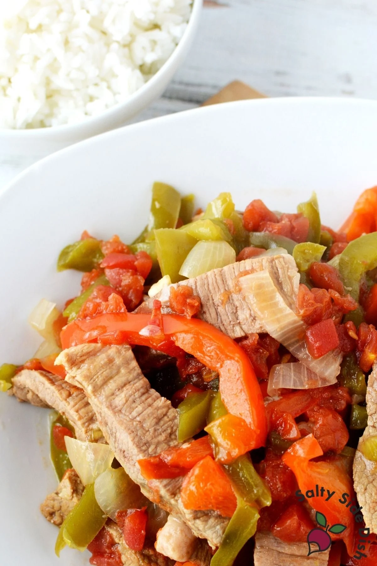 easy slow cooked sirloin beef and peppers on a plate with white rice.