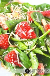 close up of strawberries and parmesan cheese in a spinach salad.